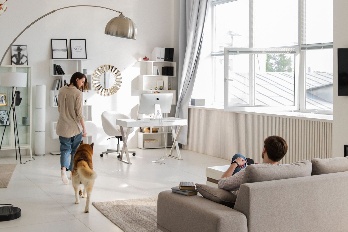 A dog standing between two people in a living room.