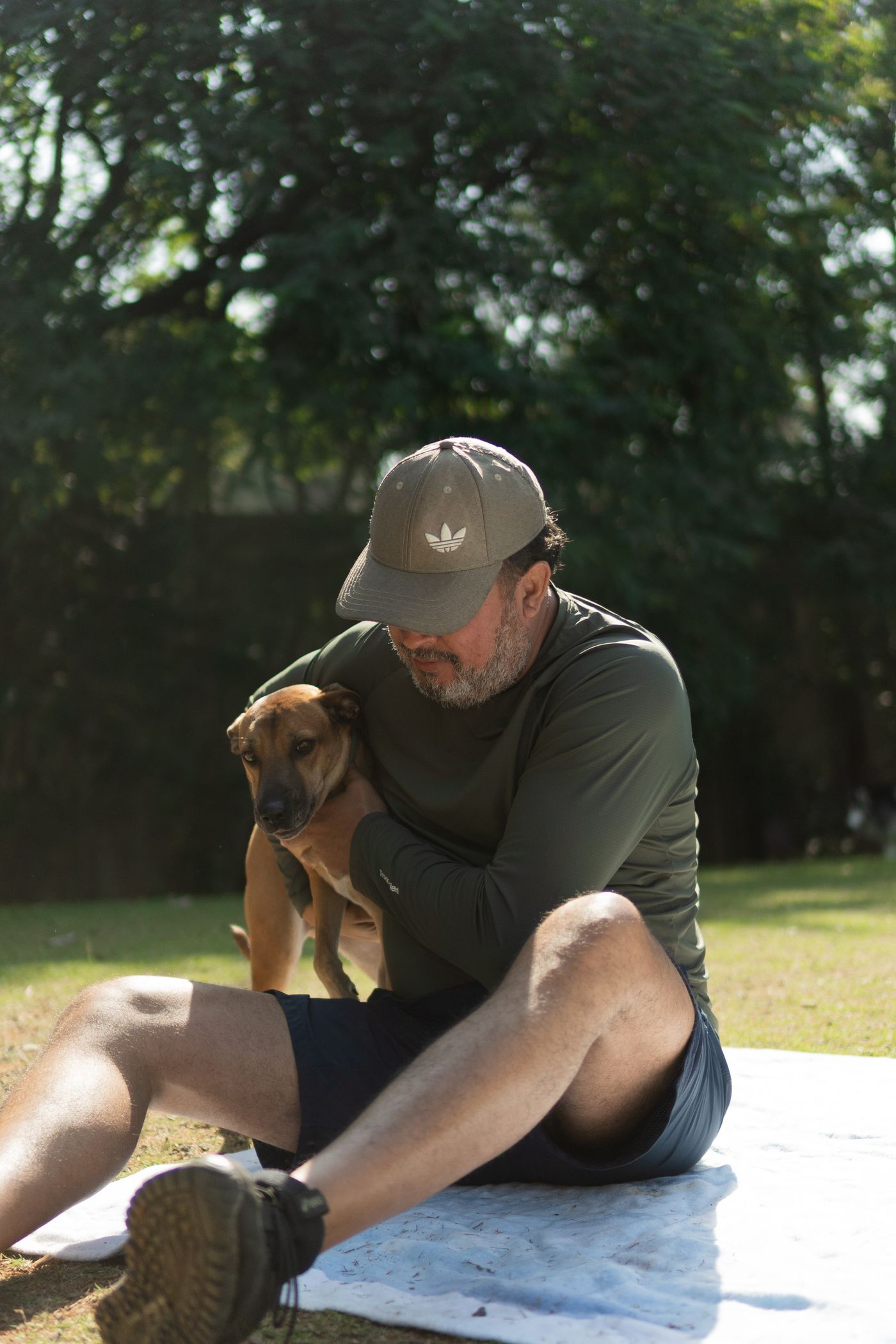 A person seated with a dog on a picnic blanket.