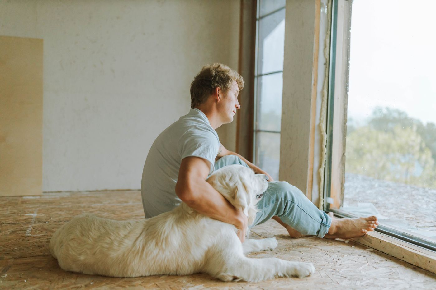 A person seated calmly with a dog beside a window.
