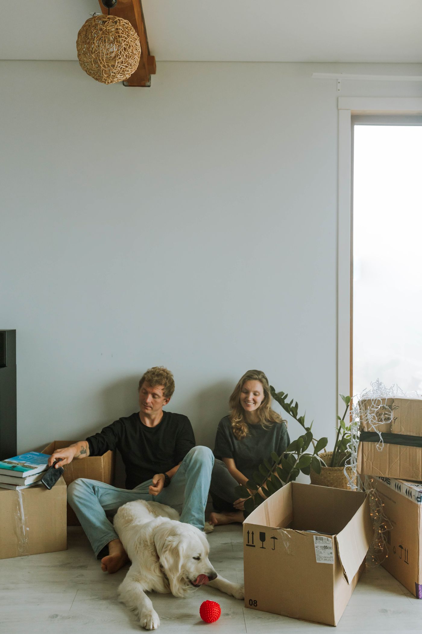 People sitting with their dog beside moving boxes.